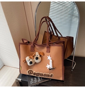 Détail d'un sac cabas en feutre marron avec peluches de chiot et broderie Pegasus