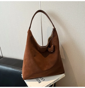 Detailed view of dark brown suede hobo bag with minimalist texture and small embossed logo