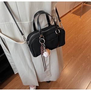 Detail of black canvas Boston bag with baseball charms and glossy top handles