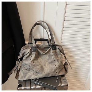 Close-up of a vintage grey tote bag with silver rivets and distressed texture on luggage