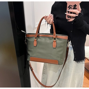 Détail du sac en nylon vert armée avec poignées en cuir marron et logo embossé