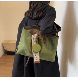 Macro detail of green quilted suede tote bag with brown leather trim and clear logo strap