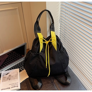 Close-up of black nylon tote bag with bright yellow drawstring detail and side pockets