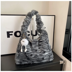 Close-up of fuzzy tiger print plush tote bag with a cute monster keychain accessory