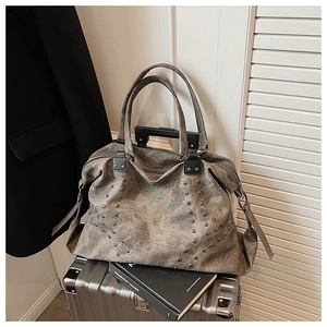 Detail of vintage matte grey tote bag with stud accents placed on a metal suitcase