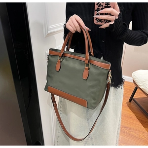 Détail du sac en nylon vert armée avec anses en cuir marron et garnitures dorées