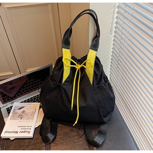 Detail of black canvas tote bag with yellow drawstring accents and side pockets