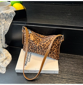 Close-up of leopard print shoulder bag with zipper detail on a dark wooden background