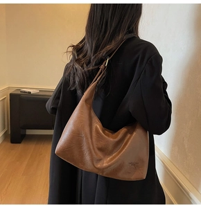 Detail of soft brown leather hobo bag with vintage slouchy texture and minimalist logo