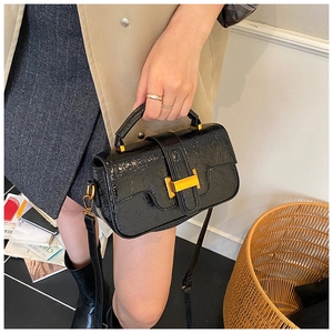 Close-up of black glossy wrinkled texture bag with a prominent golden H-shaped buckle
