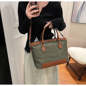 Detail of olive green tote bag with brown leather handles and adjustable shoulder strap