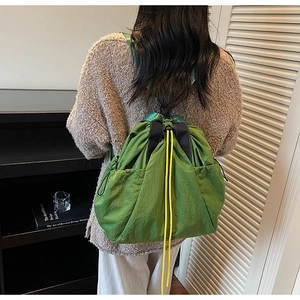 Detail of bright green drawstring tote bag featuring side pockets and yellow drawcord