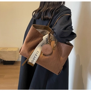 Detail of brown tote bag with geometric texture and wide brand logo shoulder strap