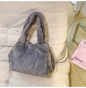 Detail of grey faux fur tote bag with large quilted texture on a cream leather sofa