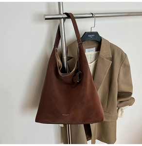 Close-up of deep brown suede tote bag with wide strap and white stitching detail