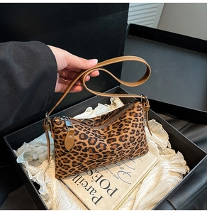Close-up of leopard print underarm bag with leather straps inside a premium gift box