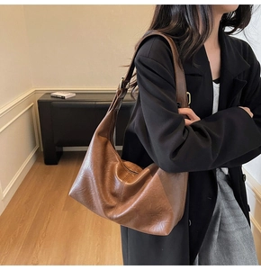 Close-up of caramel leather hobo bag with gold hardware and wide shoulder strap detail