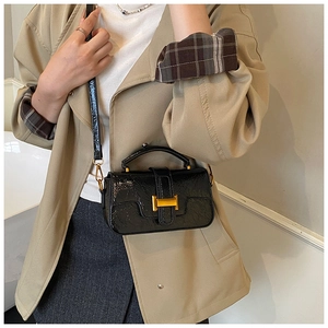 Close-up of black crossbody bag featuring a golden H-clasp and glossy wrinkled texture