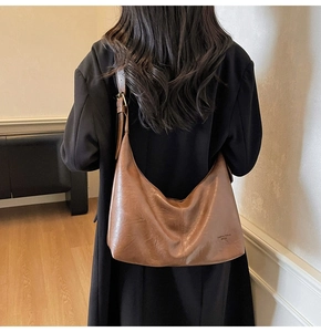 Detailed view of the adjustable strap and embossed logo on this vintage brown hobo bag