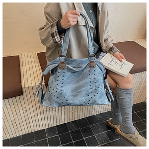 Close-up of light blue vintage tote bag with metal studs and ring handle detail