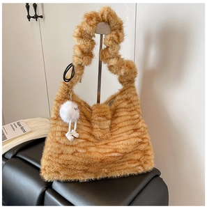 Detail of brown striped faux fur shoulder bag featuring a ruffled handle and plush charm