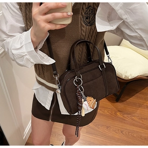 Close-up of brown suede bowling bag with unique mini baseball sports charm accessory