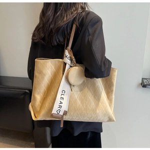 Detail of beige quilted tote bag with brown leather straps and decorative scarf