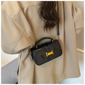 Detail view of a black glossy square crossbody bag with gold H-shaped metal buckle