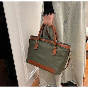 Détail du sac fourre-tout en nylon vert olive avec finitions en cuir brun et logo