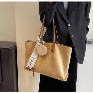 Detail of camel quilted tote bag with a round coin pouch and decorative CLEAR ribbon