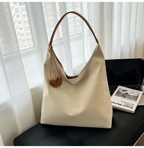 Detailed view of cream leather tote bag with brown straps in a minimalist lifestyle setting