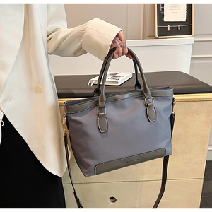 Gros plan d'un sac cabas en nylon avec garniture en cuir et détails dorés dans un décor