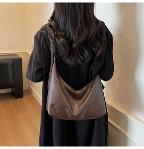 Brown vintage faux leather crescent bag styled on a black coat for daily commute