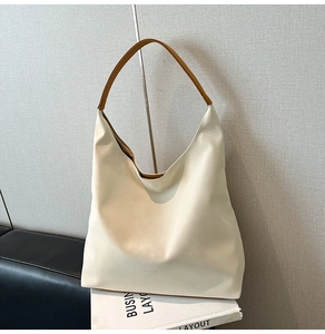 Close-up of minimalist large cream tote bag with brown handle on book background