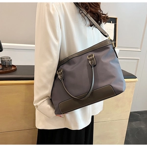 Detail of grey-blue tote bag with brown leather handles and golden metal hardware buckles
