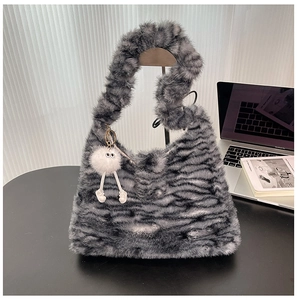 Close-up of fluffy faux fur handbag with zebra patterns and cute white plush charm