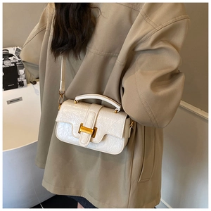 Detail of cream patent crossbody bag with faux crocodile texture and gold H clasp