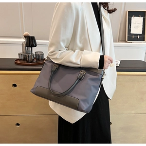 Detailed shot of two-tone nylon tote bag with leather straps on a stylish model