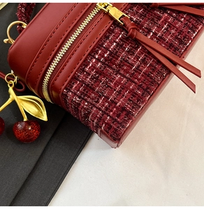 Detail of burgundy tweed handbag with leather fringe zipper and red cherry charm