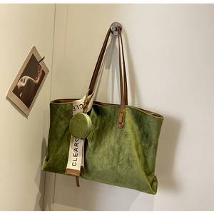 Detail of olive green quilted suede tote bag with brown leather handles and charm