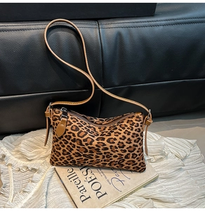 Close-up of leopard print crossbody bag with smooth leather strap and metal zipper detail