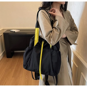 Detail of waterproof nylon drawstring backpack with vibrant yellow straps and side pocket