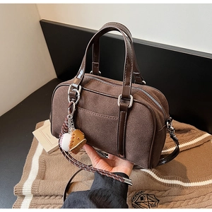 Detail of dark brown Boston bag with suede texture and baseball glove charm