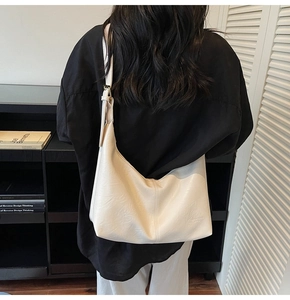 Detail of minimalist cream leather shoulder bag featuring side stitching and wide strap design