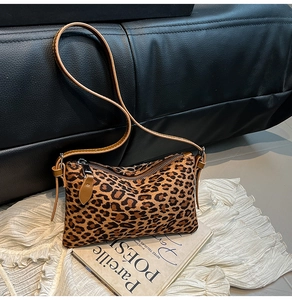 Close-up detail of leopard print suede texture and brown leather strap on luxury tote bag