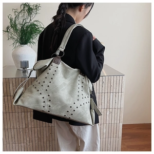 Detail of high-capacity tote bag with metal rivets on sage green matte leather
