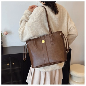 Detail of vintage brown tote bag with gold metal hardware and side drawstring texture