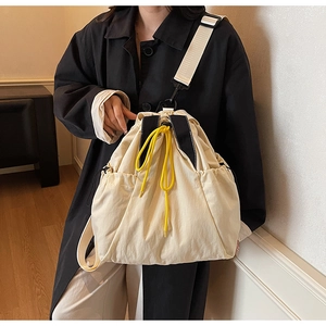 Close-up of beige drawstring bucket bag featuring vibrant yellow cords and black webbing trim
