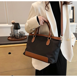 Détail du sac cabas en nylon noir avec anses en cuir marron et logo CLEAROE embossé
