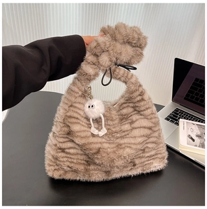 Detail of plush faux fur shoulder bag with wavy pattern and cute white fuzzy charm